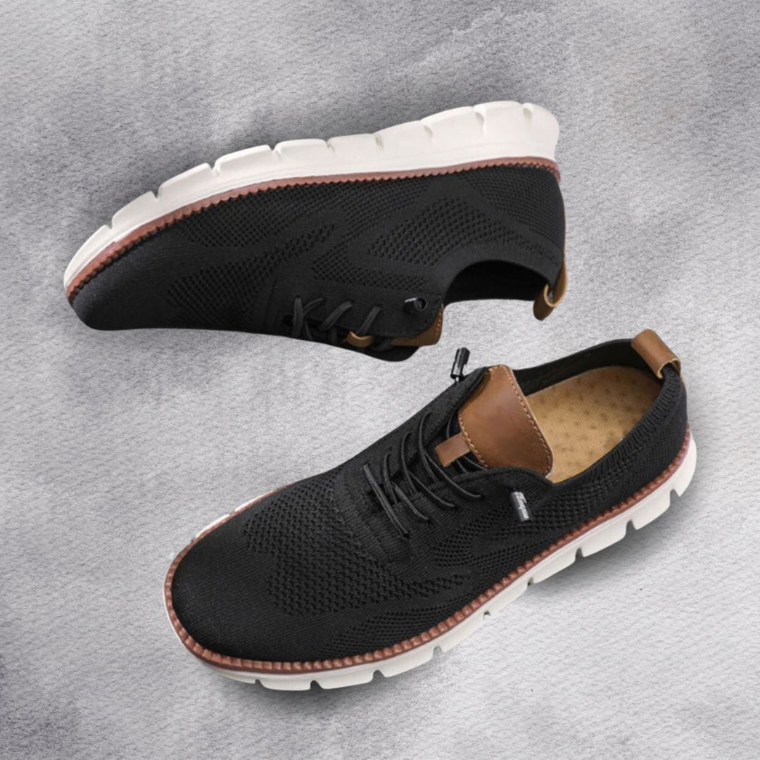 Zapatilla de senderismo negra con cordones y suela blanca dentada.