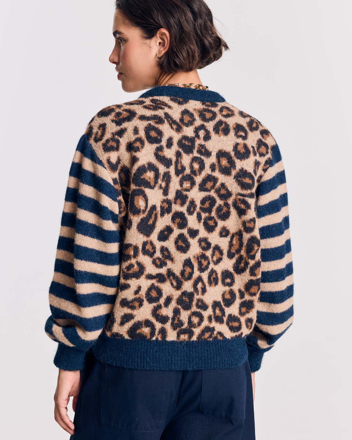 Cárdigan Idole visto por detrás, con cuerpo de leopardo y mangas a rayas azul marino y beige