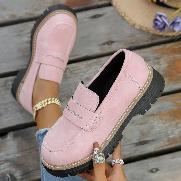 Mocasines con plataforma rosa, tipo mocasín con hebilla y suela dentada negra.